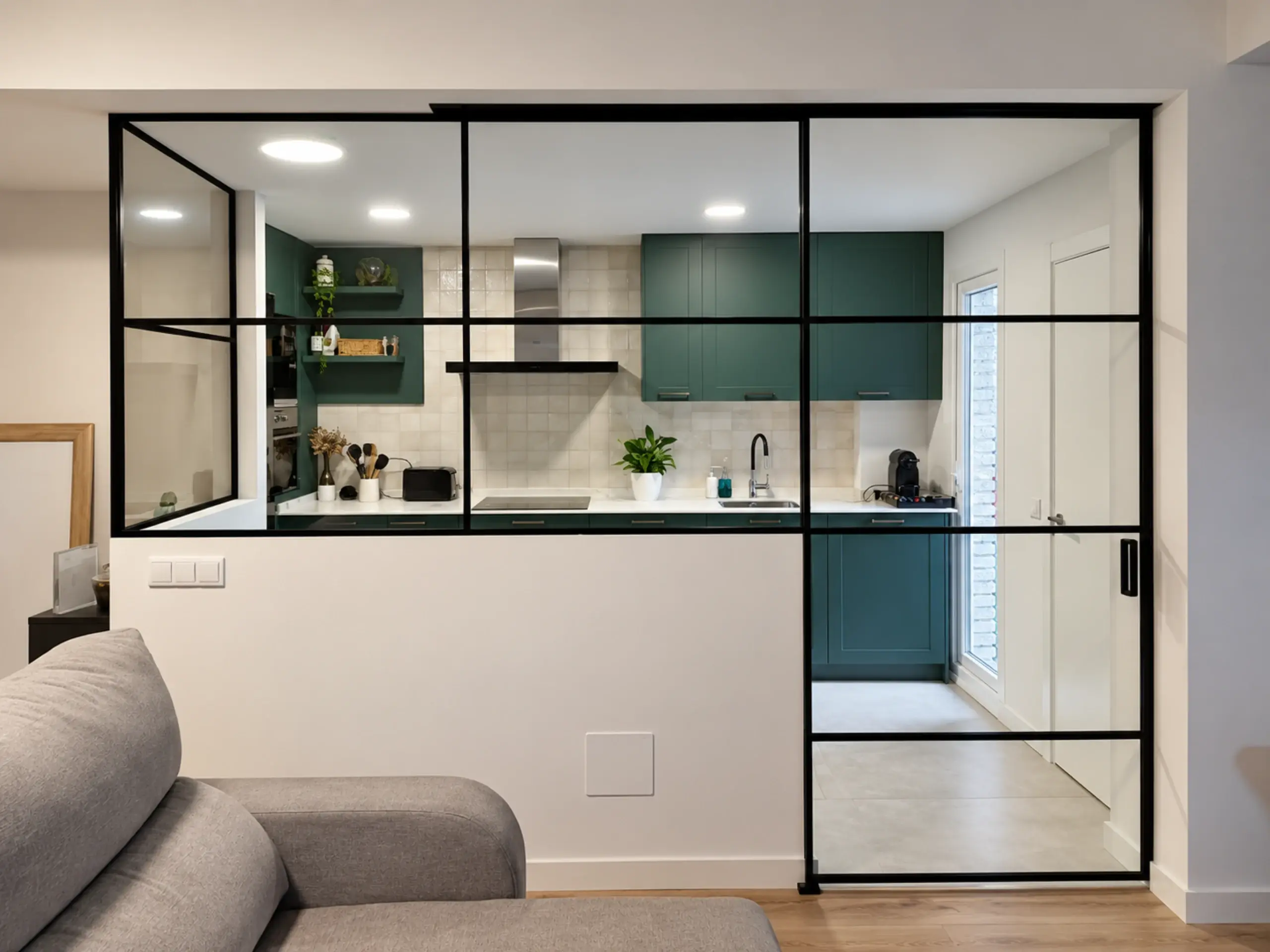 Cerramiento de cristal con perfilería negra entre el salón y la cocina verde