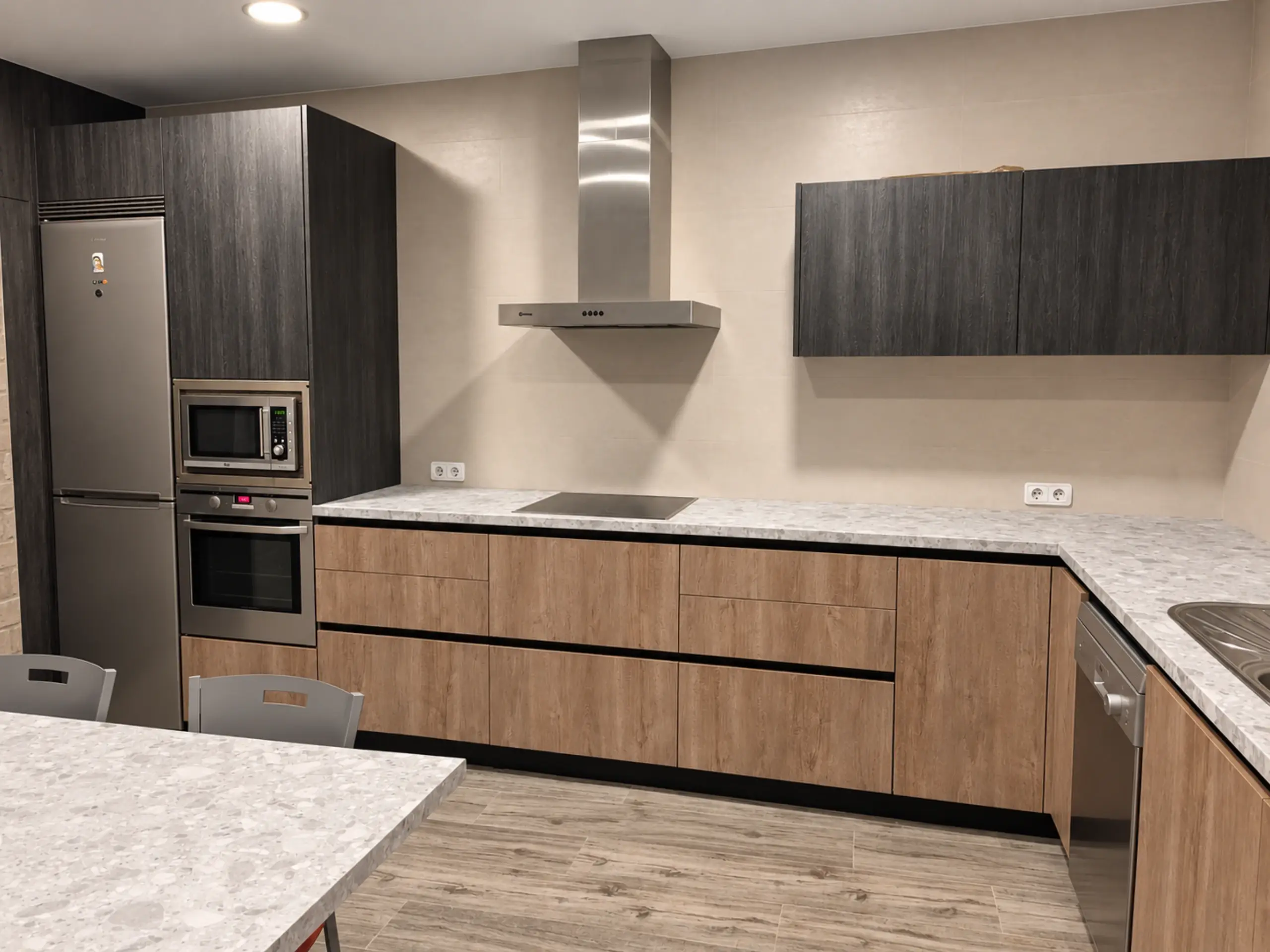 Columna oscura con frigorífico y hornos en un extremo de la cocina en L de madera